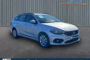 Fiat Tipo Station Wagon gris en 3/4 avant droit avec barres de toit et jantes alliage 16 pouces.