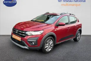 Vue 3/4 avant droite d'une Dacia Sandero Stepway rouge fusion avec barres de toit et protections noires sur les passages de roues.