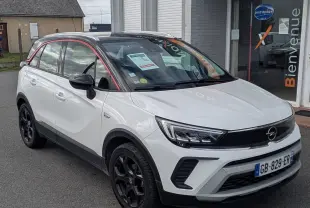 Opel Crossland X blanc vue 3/4 avant droit avec toit noir et jantes noires devant un bâtiment Distinxion.