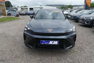 Vue frontale d'un CUPRA Formentor gris Graphene avec logo cuivré et phares LED allumés sur un parking.