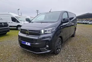 Vue 3/4 avant droit d'un Citroën Jumpy Cabine Approfondie gris titane avec feux LED allumés sur un parking extérieur.
