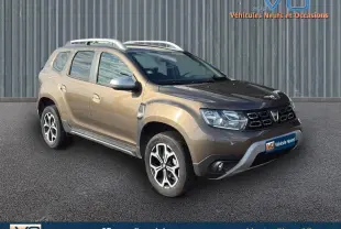SUV Dacia Duster marron vue 3/4 avant droit avec barres de toit et jantes alliage 17 pouces.