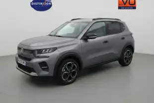 Vue 3/4 avant droit d'une Citroën C3 gris métallisé 2025 avec jantes alliage 17 pouces et barres de toit noires.