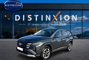 Hyundai Tucson 1.6 t-gdi 239 hybride vert en 3/4 avant droit devant un showroom Distinxion.