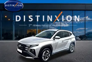 Hyundai Tucson gris shimmering en 3/4 avant droit, avec calandre noire et jantes alliage 18 pouces visibles.