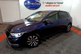 Volkswagen Golf bleu 2022 vue 3/4 avant droit avec phares LED allumés en intérieur showroom.