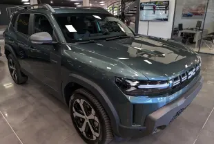 Vue 3/4 avant droite du Dacia Duster Hybrid-G 150 CH 4x4 en Vert Cèdre avec jantes bi-ton et calandre moderne.
