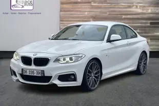 BMW Série 2 Coupé 220d M Sport blanc en 3/4 avant droit, avec phares allumés et jantes alliage distinctives.