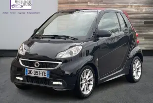 Vue 3/4 avant d'une Smart Fortwo Cabrio noire de 2014 avec toit rouge, feux diurnes allumés et jantes argentées.
