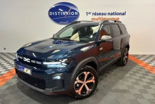 Vue 3/4 avant du Dacia Bigster bleu indigo avec jantes bi-ton et toit ouvrant en showroom.