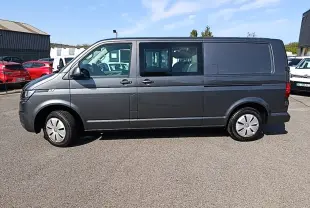 Vue latérale droite d’un Volkswagen Transporter gris foncé 2022, fourgon utilitaire avec vitres avant et portes coulissantes.