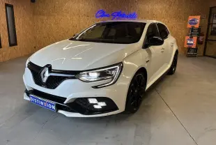Renault Mégane IV RS 280 EDC6 blanche vue 3/4 avant droit, avec jantes noires et phares allumés en intérieur.