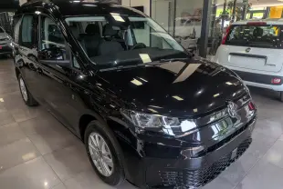 Volkswagen Caddy noir vue 3/4 avant droit en intérieur, avec phares LED et jantes alliage visibles.