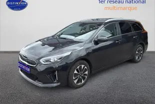 KIA CEE'D SW noire vue 3/4 avant droit, avec jantes alu et barres de toit visibles sur fond neutre.