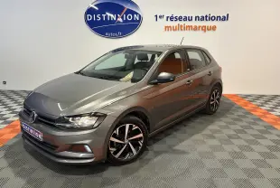 Volkswagen Polo gris vue 3/4 avant droit dans un showroom avec jantes noires et argentées.