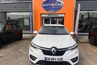 Vue frontale d'un Renault Arkana blanc perle garé devant une concession avec logo Distinxion orange.