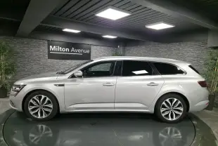 Profil côté gauche de la Renault Talisman Estate gris platine 2018 dans un showroom avec éclairage moderne.