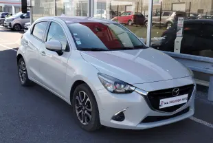 Vue 3/4 avant droite d'une Mazda2 blanche nacrée, avec jantes bi-ton et calandre noire brillante.