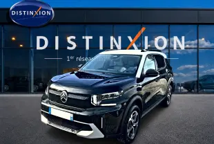 Vue 3/4 avant d'une Citroën C3 Aircross noire avec toit blanc, garée devant une vitrine Distinxion.