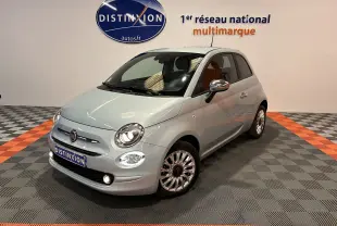 Vue 3/4 avant d'une Fiat 500 gris clair avec jantes alliage et rétroviseurs chromés en showroom.