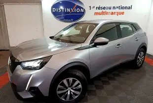 Peugeot 2008 gris clair vue 3/4 avant droit dans un showroom avec phares LED et jantes alliage.