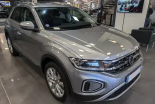 Volkswagen T-Roc gris pyrite en 3/4 avant droit, mettant en valeur ses optiques LED et jantes alliage 18 pouces.