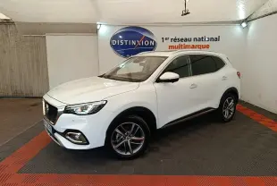 Vue 3/4 avant droit d’un SUV MG EHS blanc, avec jantes alliage et calandre chromée dans un showroom.