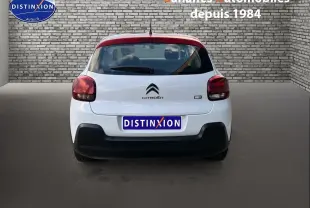 Vue arrière d'une Citroën C3 blanche de 2018 avec feux rouges et pare-chocs noir mat dans un décor urbain.