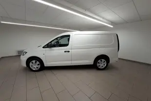 Vue de profil côté gauche d’un Volkswagen Caddy Cargo Maxi blanc Candy 2026 dans un intérieur neutre.