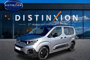 Citroën Berlingo Steel Grey en 3/4 avant droit, avec jantes noires et barres de toit visibles devant showroom Distinxion.