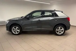 Audi Q2 35 TFSI S Line gris Daytona vu de profil côté gauche dans un intérieur neutre.