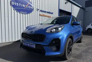 KIA Sportage 1.6 CRDI bleu en 3/4 avant droit, avec calandre noire et jantes noires, stationné devant un bâtiment.