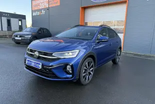 Volkswagen Taigo bleu récif métallisé en 3/4 avant droit avec jantes alliage noires brillantes sur parking.