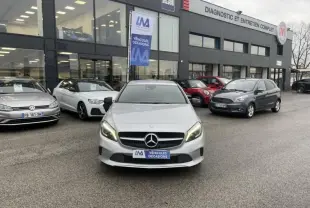 Vue avant d'une Mercedes Classe A 200 D Sensation gris métal avec phares allumés sur parking de concession.