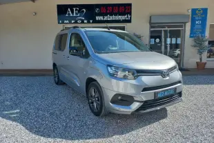 Toyota Proace City Verso gris vue 3/4 avant droit, avec calandre noire et jantes alliage, stationné devant un bâtiment.