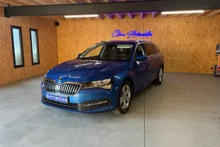 Vue 3/4 avant droite d'une Skoda Superb Combi bleu métallisé dans un showroom avec éclairage intérieur et mur en bois.