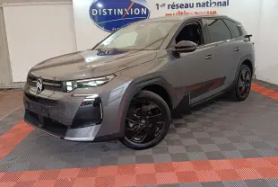 Citroën C5 Hybride gris foncé vue 3/4 avant avec jantes noires et calandre distinctive en intérieur showroom.