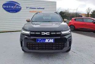 Vue avant d'un Dacia Bigster noir nacré avec calandre marquée et phares LED fins, stationné devant un mur publicitaire.