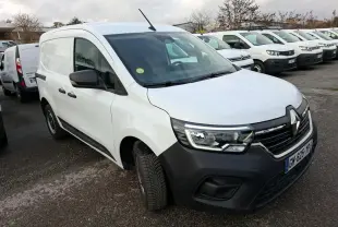 Renault Kangoo blanc en 3/4 avant droit sur parking gravillonné, avec calandre noire et phares allumés.