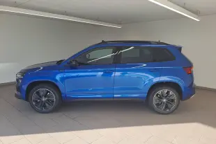 Profil côté gauche d'un Skoda Karoq 2025 bleu RS avec toit panoramique ouvrant et jantes alliage distinctives.