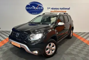 Dacia Duster noir en 3/4 avant droit, avec jantes alliage, barres de toit argentées et antibrouillards allumés.
