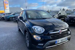 Vue 3/4 avant d'un FIAT 500X Cross noir 2016 avec calandre chromée et feux ronds allumés sur parking.