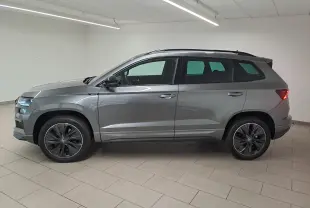 Vue latérale droite d'un Skoda Karoq gris graphite métallisé 2025 avec jantes noires et hayon électrique en intérieur.