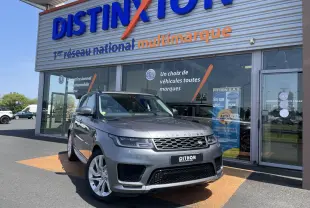 Range Rover Sport gris Eiger en 3/4 avant droit, avec jantes alu 21 pouces devant un showroom Distinxion.