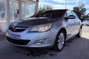 Opel Astra gris vue 3/4 avant droit sous abri, phare allumé et plaque Distinxion visible