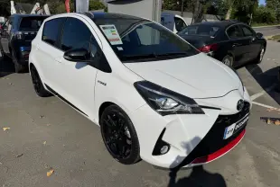 Toyota Yaris Hybride 100CH GR SPORT blanc vue 3/4 avant droit avec jantes noires et détails rouges sur le pare-chocs.
