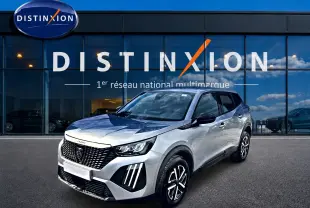 Peugeot 2008 gris en 3/4 avant droit, avec calandre noire et phares LED distinctifs, devant une vitrine Distinxion.