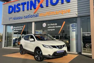 Nissan Qashqai blanc nacré en 3/4 avant droit devant un showroom Distinxion, avec jantes noires distinctives.