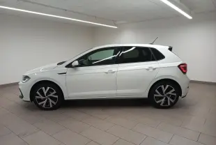 Vue de profil côté gauche d'une Volkswagen Polo blanche avec vitres arrière surteintées et jantes R-Line distinctives.