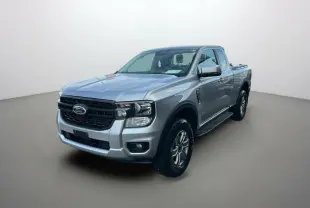 Ford Ranger 2026 gris iconic en 3/4 avant droit, avec marchepieds latéraux et calandre noire distinctive.